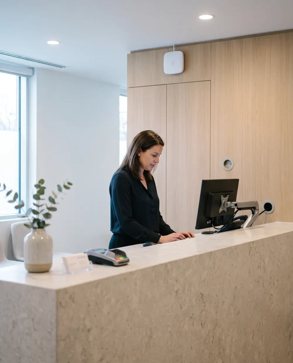 Illustration: a practice manager working at a clinic reception counter.